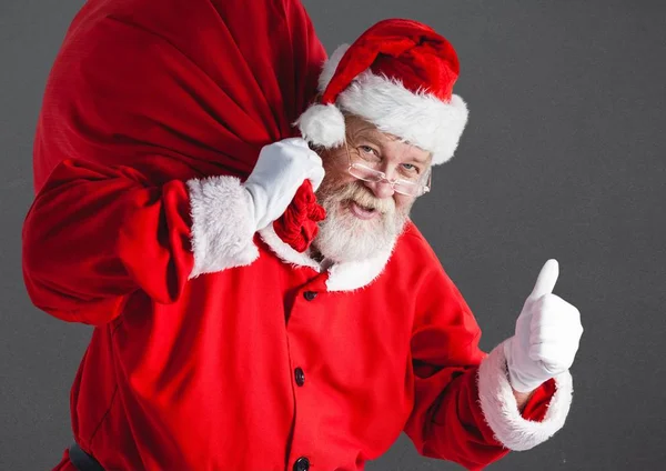 Kerstman met cadeau zak duimen opdagen — Stockfoto
