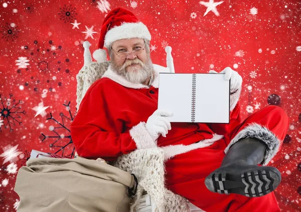 Weihnachtsmann sitzt auf Stuhl und zeigt Tagebuch — Stockfoto