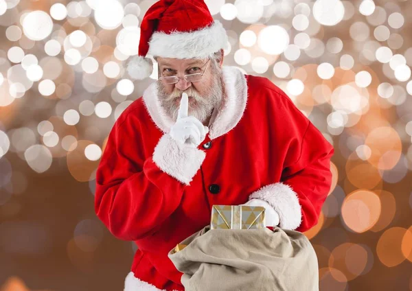 Weihnachtsmann mit Finger auf den Lippen hält Geschenktüte — Stockfoto