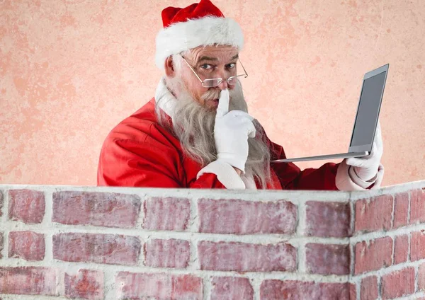 Kerstman met de vinger op de lippen met laptop — Stockfoto