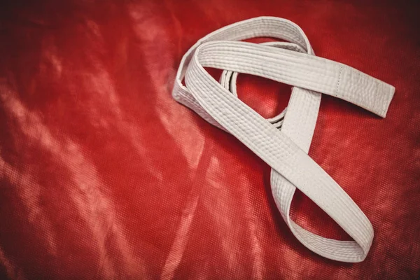 Cinturão branco de karatê no fundo vermelho — Fotografia de Stock
