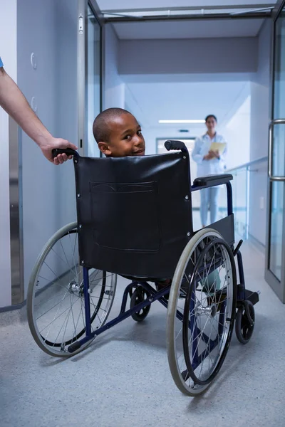 Menino sentado em cadeira de rodas no corredor — Fotografia de Stock