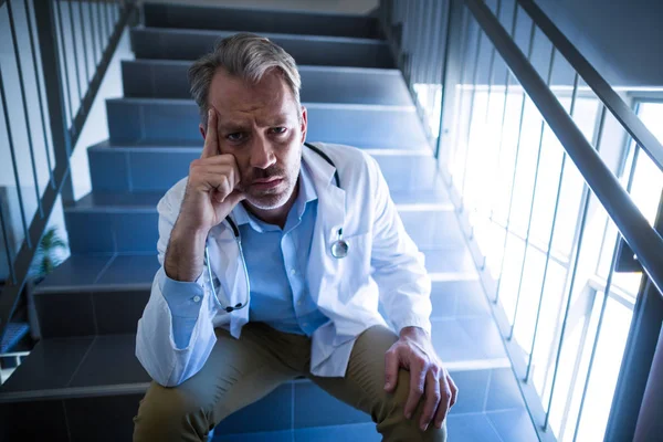 Sad doctor sitting on staircase — Stock Photo, Image