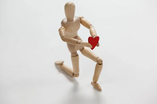 Figurine en bois agenouillée et tenant un cœur — Photo