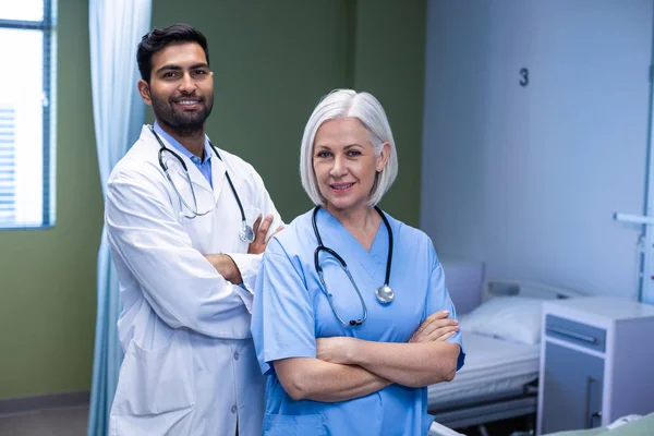 Dokter en verpleegster permanent met gekruiste armen — Stockfoto