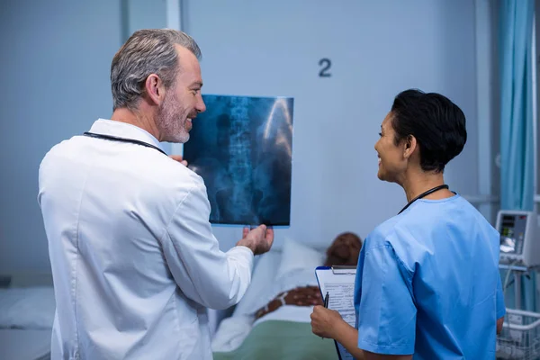 Médico e enfermeira discutindo raio-x na enfermaria — Fotografia de Stock