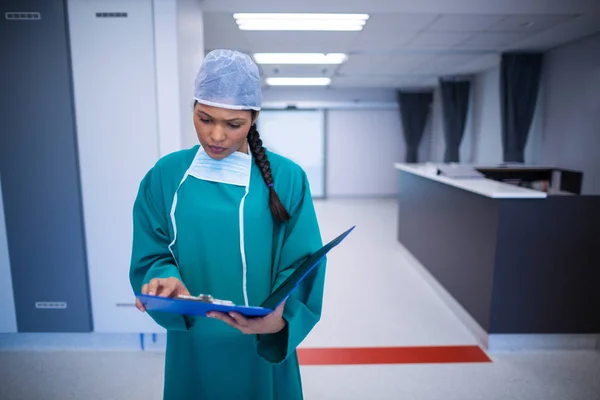 Surgeon checking report in corridor — Stock Photo, Image