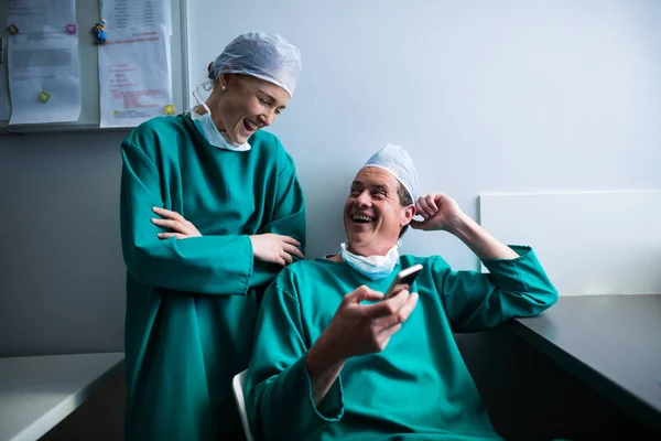 Surgeons interacting while using phone — Stock Photo, Image