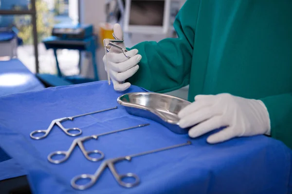 Mid section of surgeon holding surgical tool — Stock Photo, Image