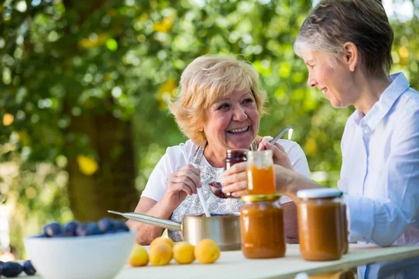 Äldre kvinnor fyllning sylt i en flaska — Stockfoto