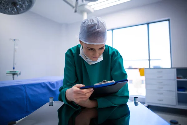 Female surgeon reading reports — Stock Photo, Image