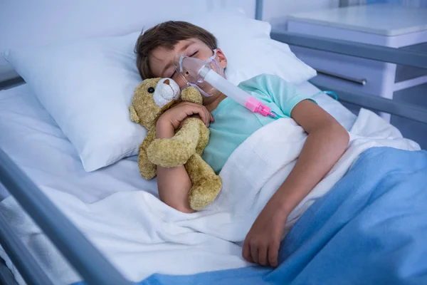 Patient with oxygen mask relaxing on bed in ward — Stock Photo, Image