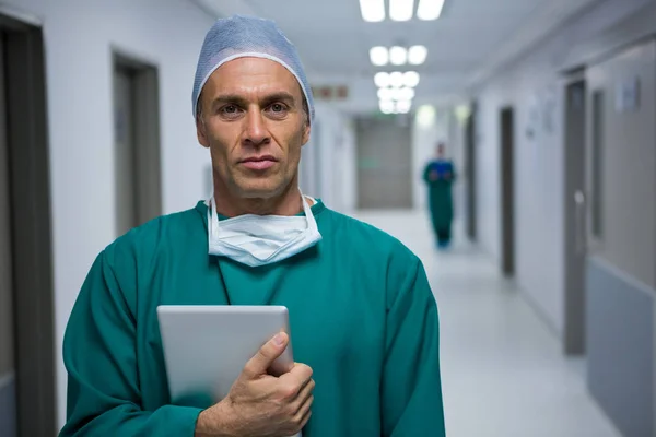 Surgeon standing with digital tablet in corridor — Stock Photo, Image