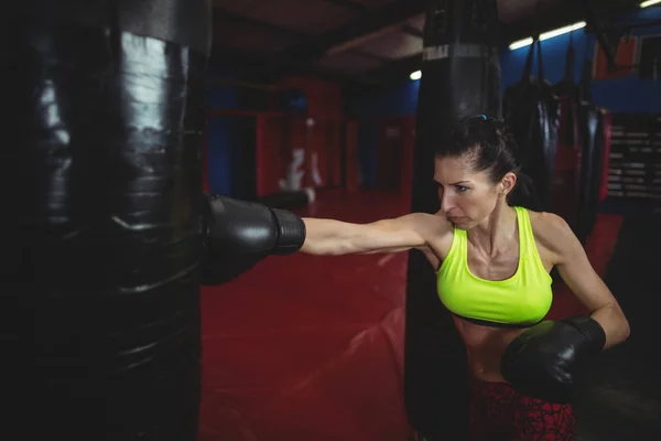 Boxeadora femenina practicando boxeo con saco de boxeo — Foto de Stock