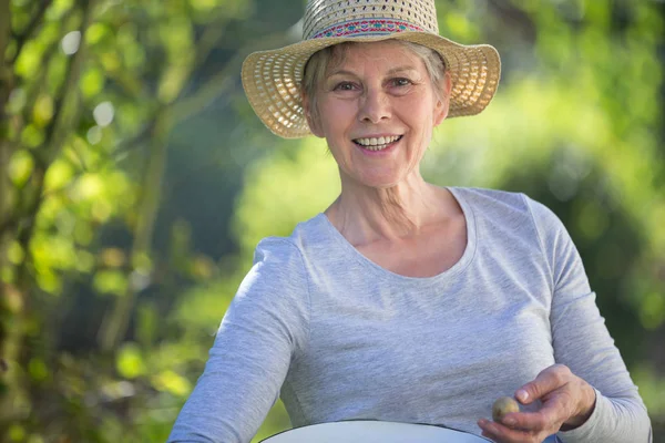 Femme âgée portant des pommes de terre dans un bol — Photo