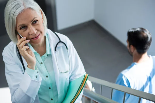 Läkare pratar i mobiltelefon medan — Stockfoto