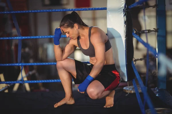 Female boxer crouching in boxing ring — Stock Photo, Image