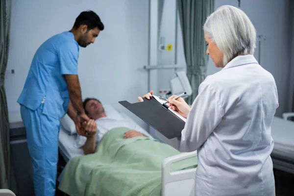 Médico e cirurgião consultando paciente na enfermaria — Fotografia de Stock