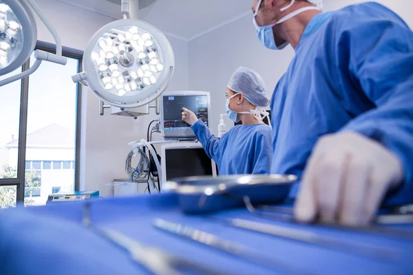 Мужчина и женщина-хирург с помощью аппарата мониторинга пациентов — стоковое фото