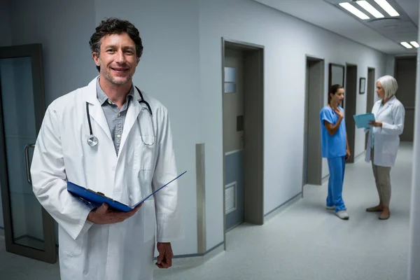 Doctor holding medical report in corridor — Stock Photo, Image