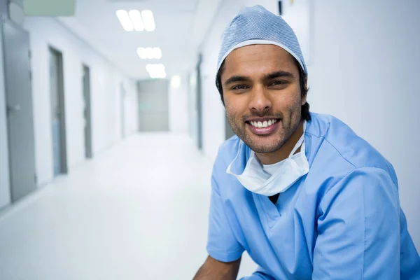 Usmívající se chirurg sedí v chodbě — Stock fotografie