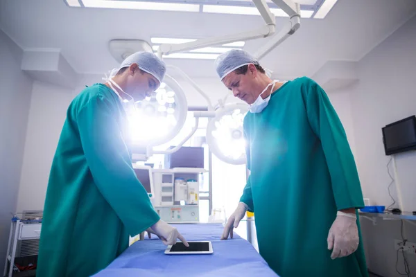 Хирурги с помощью цифрового планшета в операционной — стоковое фото