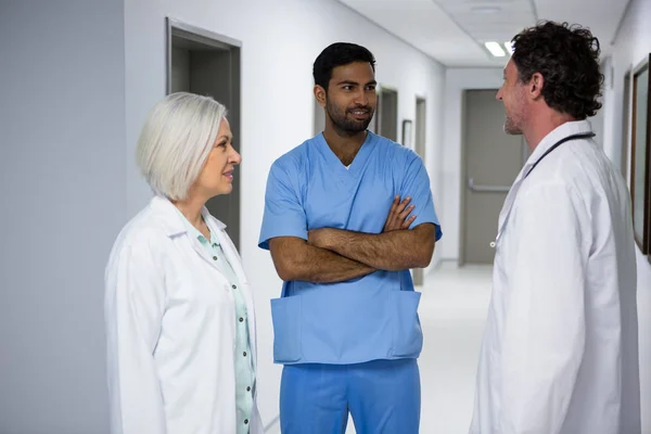 Doctors and surgeon interacting in corridor — Stock Photo, Image
