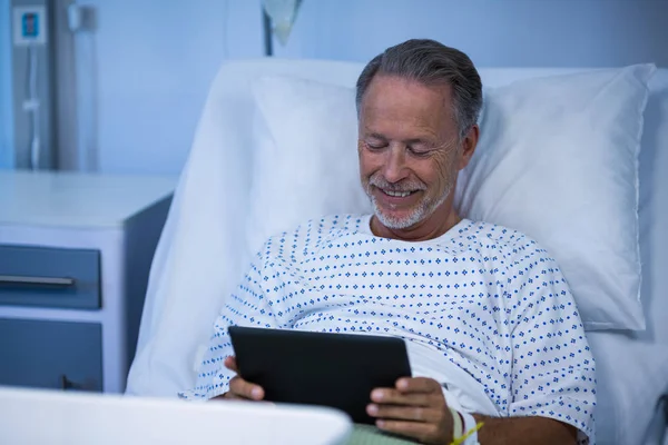 Хворий пацієнт сидить на ліжку і використовує планшет — стокове фото