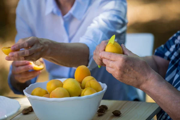 Senior couples removing seeds of apricot fruits — Stock Photo, Image