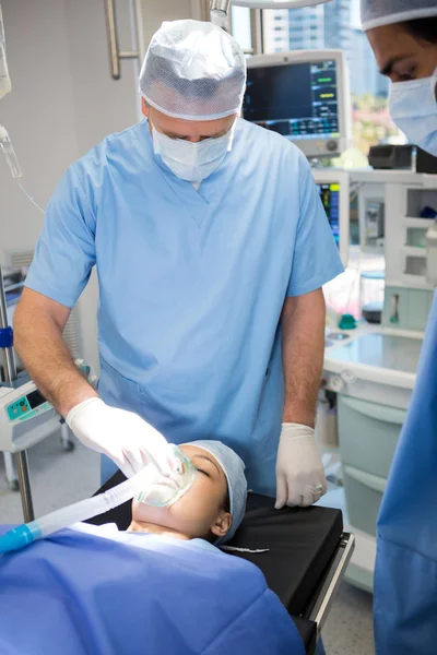 Врач надевает кислородную маску на лицо пациента — стоковое фото