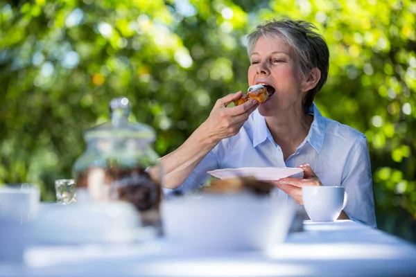 Senior vrouw zoet eten in de tuin — Stockfoto