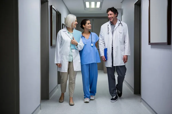 Médicos y cirujanos interactuando en corredor —  Fotos de Stock