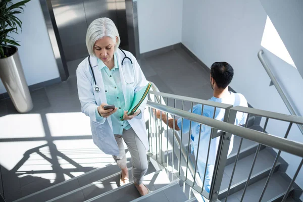 Doctor using phone while walking on staircase — Stock Photo, Image