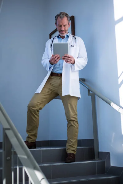 Doctor using digital tablet on staircase — Stock Photo, Image