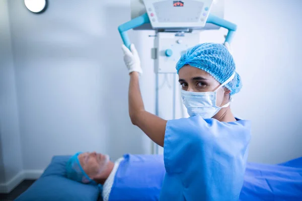 Pielęgniarka regulacji aparatu rentgenowskiego przez pacjenta — Zdjęcie stockowe