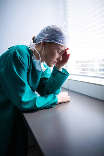 Tensed female surgeon standing at window — Stock Photo, Image