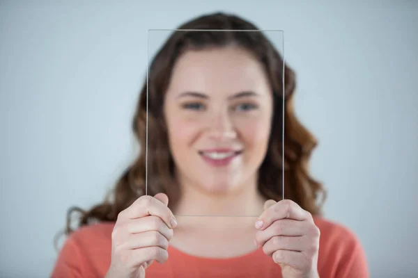 Femme tenant une feuille de verre contre son visage — Photo