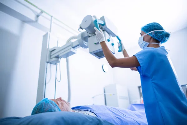 Krankenschwester stellt Röntgengerät über Patientin ein — Stockfoto