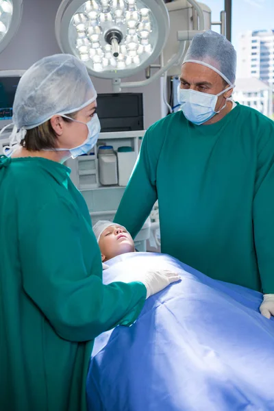 Surgeons interacting while operating patient — Stock Photo, Image