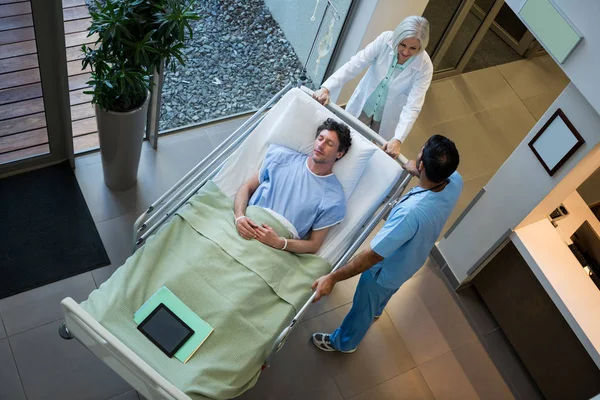 Doctors interacting while patient lying on emergency stretcher — Stock Photo, Image