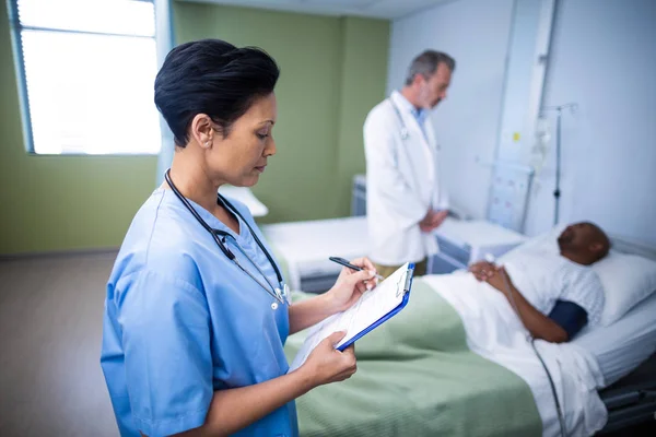 Krankenschwester schreibt bei Besuch in Station auf Klemmbrett — Stockfoto