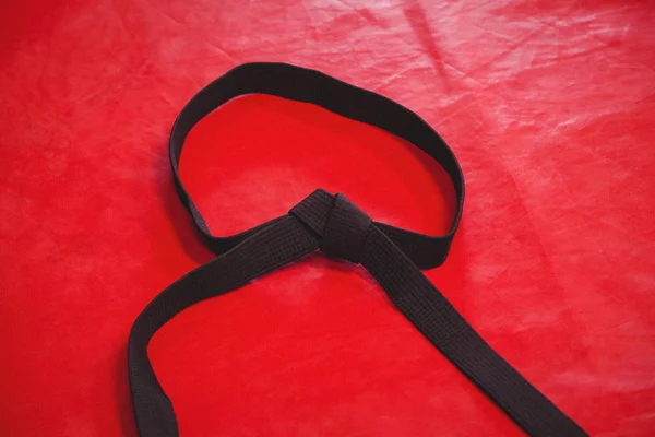 Karate siyah kuşak kırmızı zemin üzerine — Stok fotoğraf