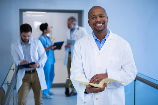 Macho médico segurando arquivo no corredor — Fotografia de Stock