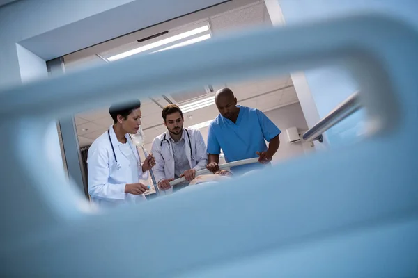 Doctors adjusting iv drip while patient lying on bed — Stock Photo, Image