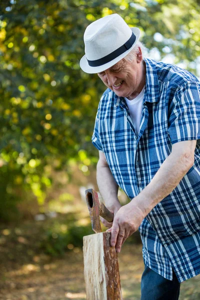 Senior man hakken van brandhout — Stockfoto
