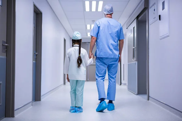 Доктор и девушка идут по коридору в больнице — стоковое фото