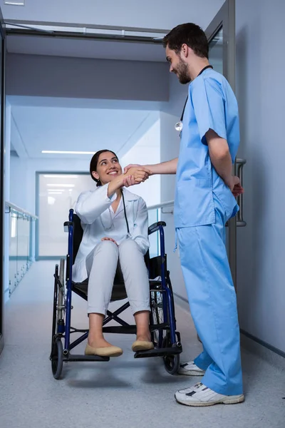 Femme médecin en fauteuil roulant serrant la main avec infirmière — Photo