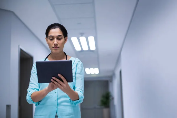 Женщина-врач с помощью цифрового планшета в коридоре — стоковое фото