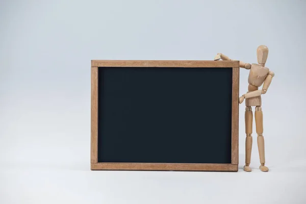 Wooden figurine beside a slate board — Stock Photo, Image
