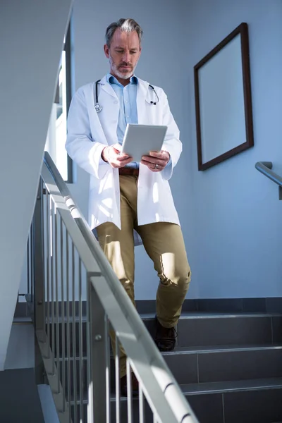 Doctor using digital tablet on staircase — Stock Photo, Image